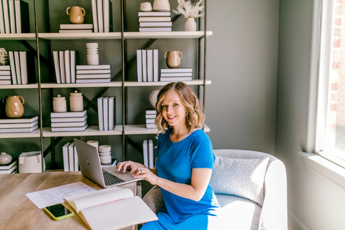 A casually dressed woman smiling at the camera in a bright workspace